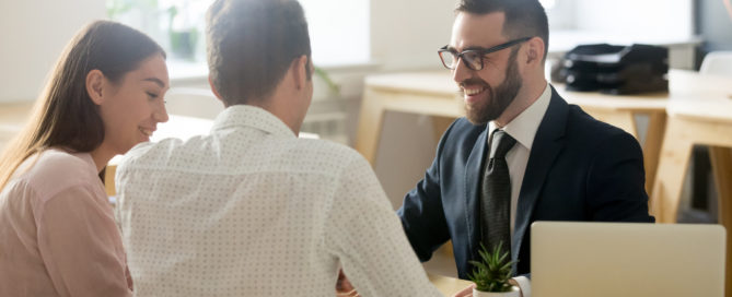 Friendly lawyer or financial advisor in suit consulting young couple